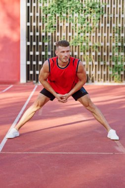Spor sahasındaki spor salonunda kırmızı formalı bir sporcu.