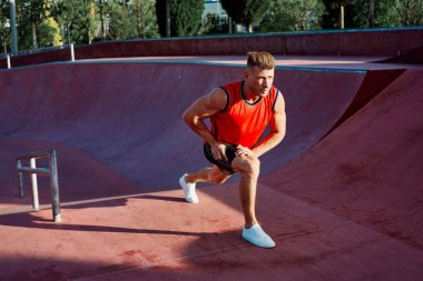 Kırmızı formalı sporcu vücut geliştirme egzersizi yapıyor.