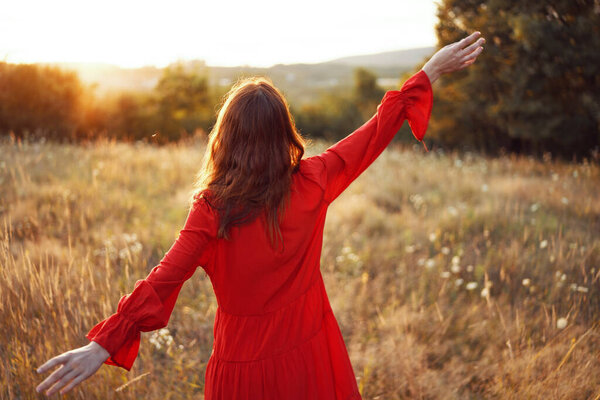Woman in a red dress in a field in nature summer landscape freedom. High quality photo