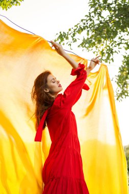 Kırmızı elbisenin arka planında açık havada sarı bir bez var.