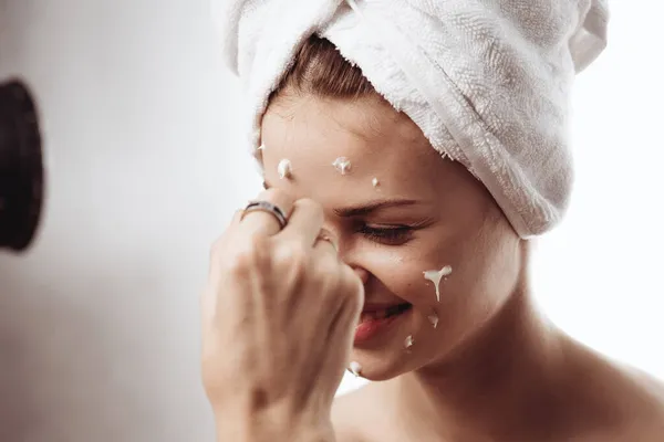Wanita ceria dengan handuk putih di kepalanya wajah krim perawatan kulit — Stok Foto