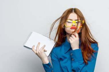 Not defteri ve kalem takan, sarı gözlüklü profesyonel bir iş kadını.