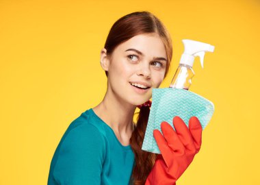 Deterjanlı temizlikçi kadın sarı arka planda.