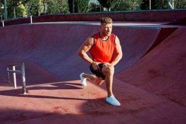 Kırmızı formalı sporcu vücut geliştirme egzersizi yapıyor.