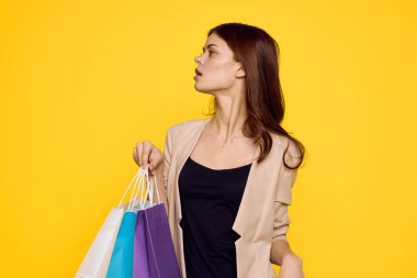 Neşeli kadın, çok renkli. Duygularını alışverişe taşıyor. Moda sarı arka plan.