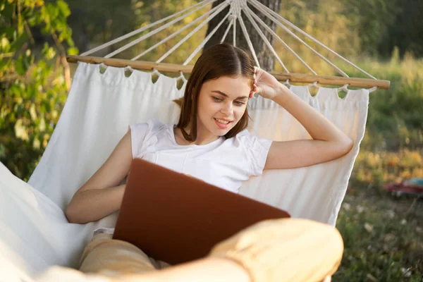Vrolijk vrouw ligt in een hangmat met een laptop vakantie internet reizen — Stockfoto