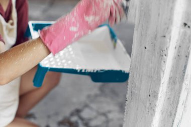 Neşeli kadın bir evin içini boyuyor.