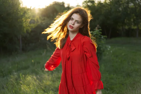 Привлекательная женщина в красном платье, позирующая в зеленой траве — стоковое фото