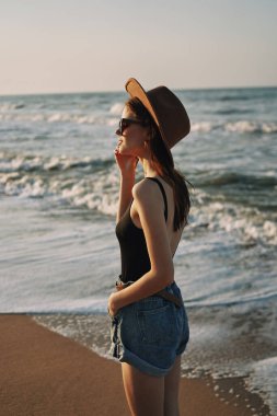 Kumsalda yürüyen bir kadın, tatil güneşinde seyahat ediyor.