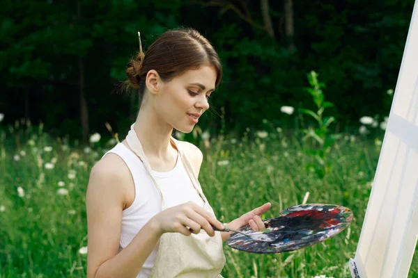 Жінка в білій сукні з палітрою фарб на малюнку природи — стокове фото