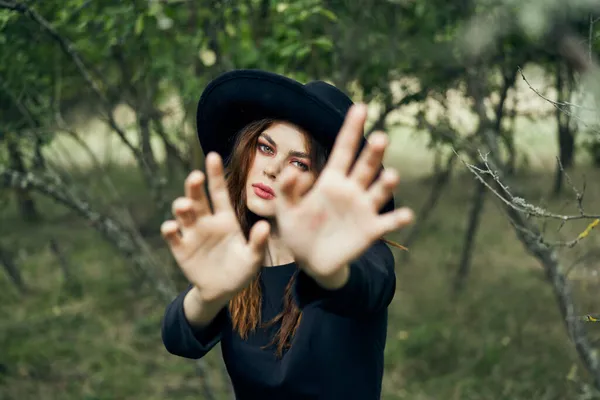 黒の帽子に身を包んだ女が魔法のファンタジーを手に — ストック写真