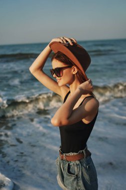 Kumsalda yürüyen bir kadın, tatil güneşinde seyahat ediyor.