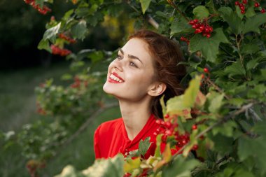 Kırsal alanda kırmızı gömlekli neşeli bir kadın.