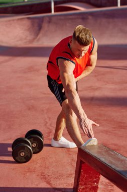 Sporcu adam dışarıda oyun sahasında spor yapıyor.