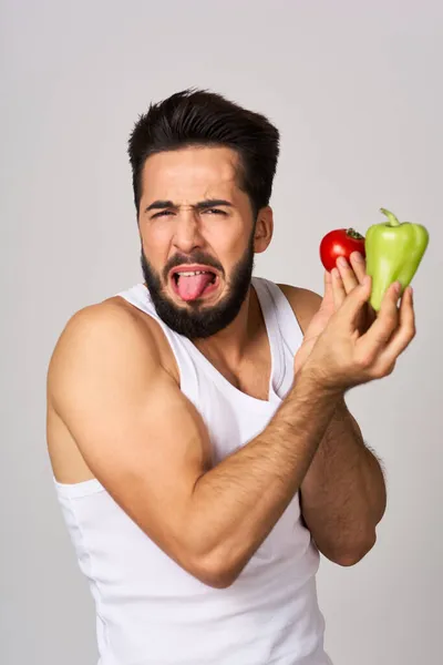 Een man in een wit t-shirt met groenten in zijn handen gezonde voeding — Stockfoto