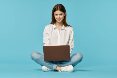 Dizüstü bilgisayarı olan bir kadın yerde oturup internet teknolojisi öğreniyor.