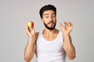 Beyaz tişörtlü bir adam taze meyve elmalı vitaminler izole edilmiş arka plan.