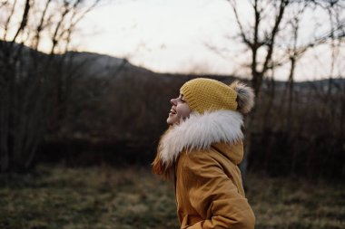 Dışarıda ceketli bir kadın sonbaharda temiz hava alıyor.