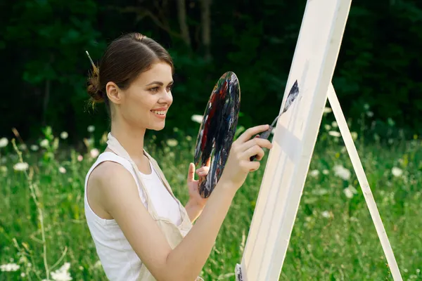 Neşeli kadın bir palet doğa resmi çiziyor. — Stok fotoğraf