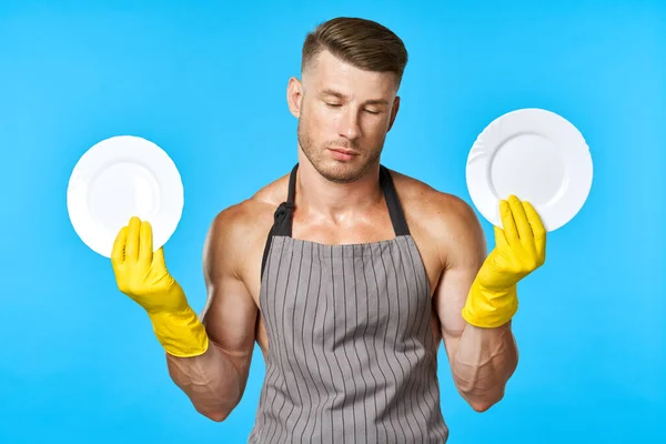 Vidám ember kötényben mosogatás edények házimunka kék háttér — Stock Fotó