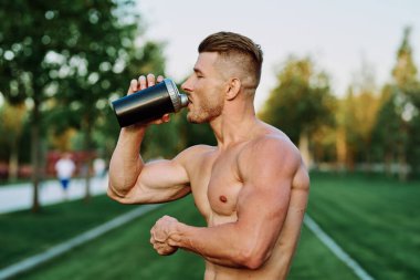 Parktaki egzersiz motivasyonunda kaslı vücutlu atletik bir adam.