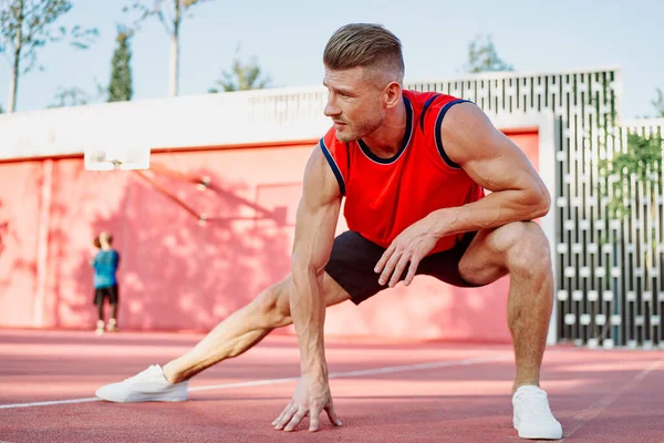 Spor salonunda spor yapan kırmızı tişörtlü bir adam egzersiz yapıyor.