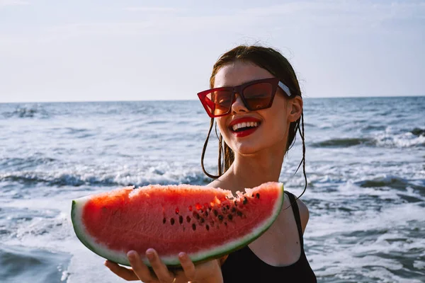 Ellerinde karpuz olan siyah mayo giymiş güzel bir kadın.