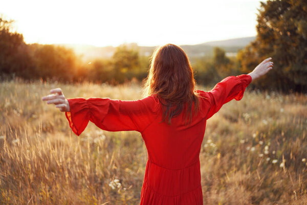 woman in red dress in the field with hands raised up posing