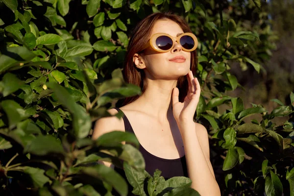 Vidám nő visel napszemüveg zöld levelek természet nyári pózol — Stock Fotó