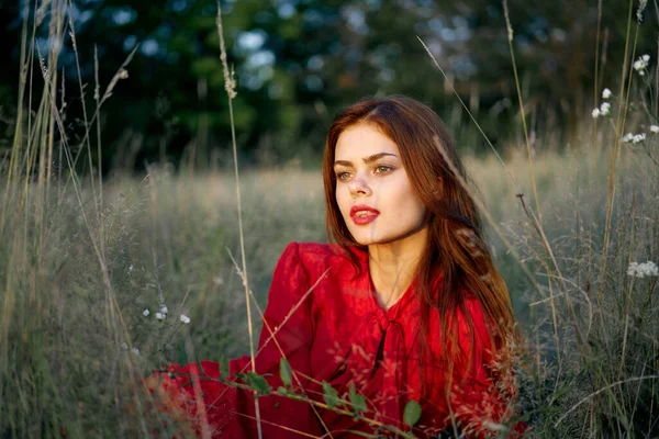 Женщина в красном платье лежит на траве в поле — стоковое фото