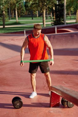 Dambılı erkek sporcu parkta el eğitiminde.