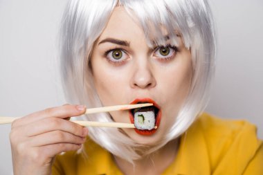 Beyaz peruklu güzel bir kadın ve Japon yemek çubuklarıyla suşi.