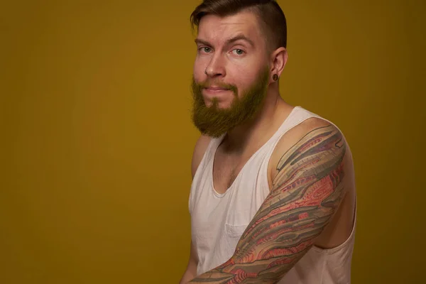 Веселий бородатий чоловік у білій футболці з татуюваннями хуліганів на руках — стокове фото