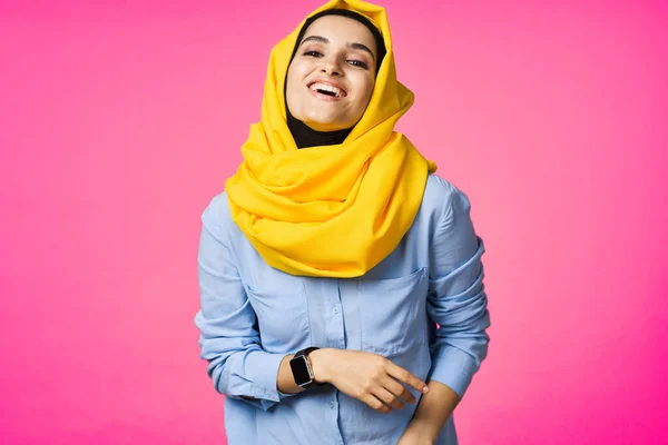 Femme gaie en jaune hijab technologie montre électronique utilisateur fond rose — Photo