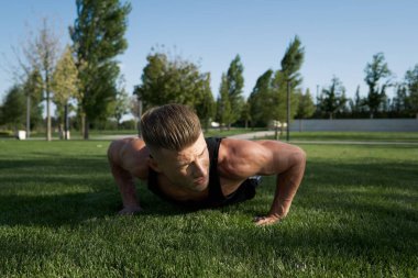 Parktaki spor salonunda vücudunu şişiren atletik adam. Temiz hava.