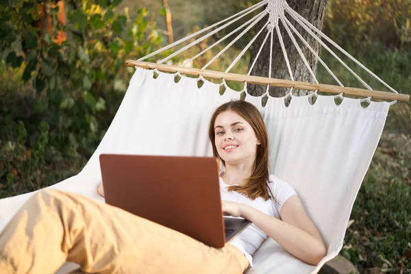 Kobieta na zewnątrz z laptopem leży w hamaku technologia czasu wolnego — Zdjęcie stockowe