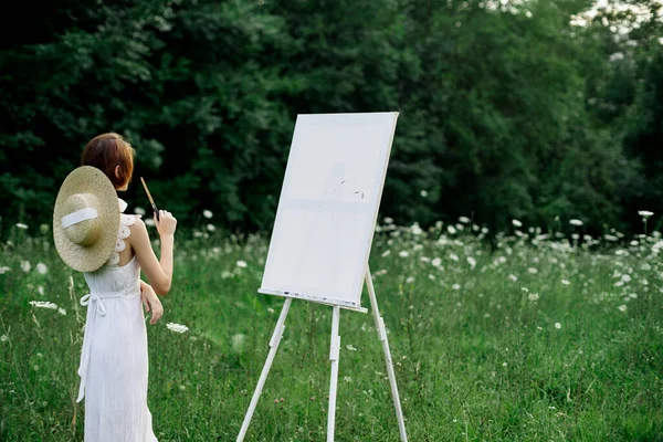 穿着白衣的女人在户外画一幅图画，这是一种创造性的业余爱好 — 图库照片