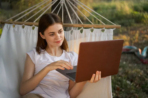 Kobieta z laptopem i leży w hamaku wakacje natura freelance — Zdjęcie stockowe