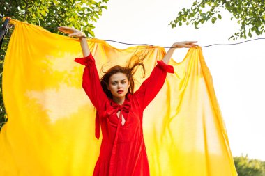 Sarı arka plan pozu veren kırmızı elbiseli çekici kadın.