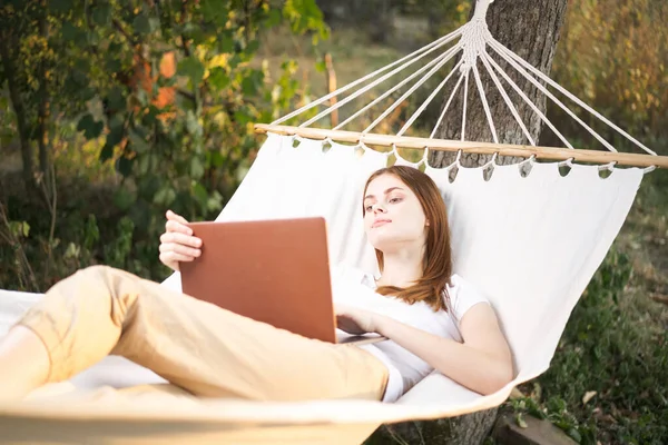 Vrouw buiten met laptop ligt in hangmat vrijetijdsbesteding technologie — Stockfoto