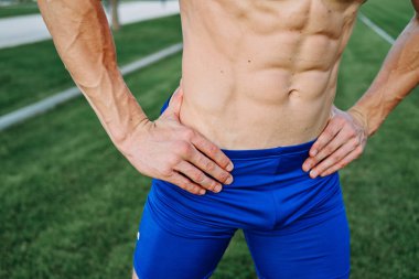 Spor yaparken parkta kasları şişmiş, spor yapan bir adam.