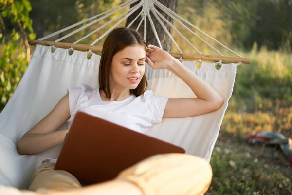 Vrolijk vrouw ligt in een hangmat met een laptop vakantie internet reizen — Stockfoto