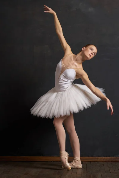 Mulher bailarina em um branco tutu dança posando desempenho fundo escuro — Fotografia de Stock