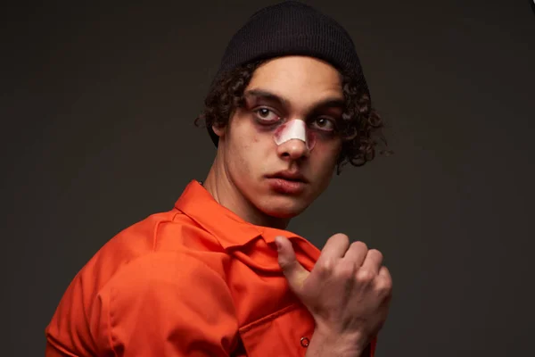 Hombre con la nariz rota moretones bajo los ojos naranja camisa crimen — Foto de Stock