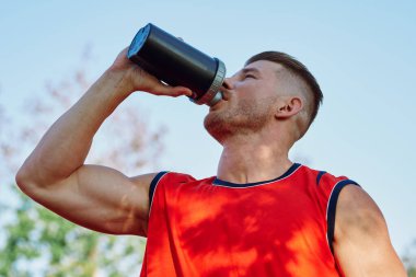 Sportif adam parkta dinleniyor, bankta atıştırıyor.