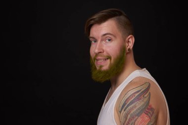 Kollarında dövmeleri olan sakallı bir adam.