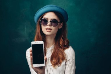 Mavi şapkalı şık bir kadın. Elinde telefon, iletişim teknolojisi var.