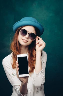 Mavi şapkalı şık bir kadın. Elinde telefon, iletişim teknolojisi var.