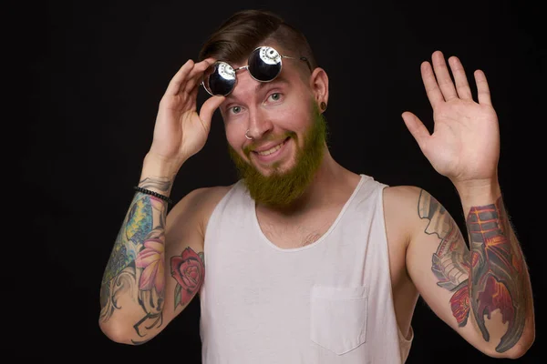 Knappe man met tatoeages op zijn armen mode zonnebril donkere achtergrond — Stockfoto