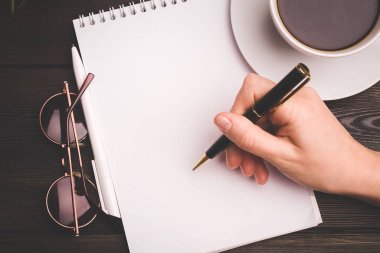Kahve fincanı not defterinde kalem öğrenme bürosu var.